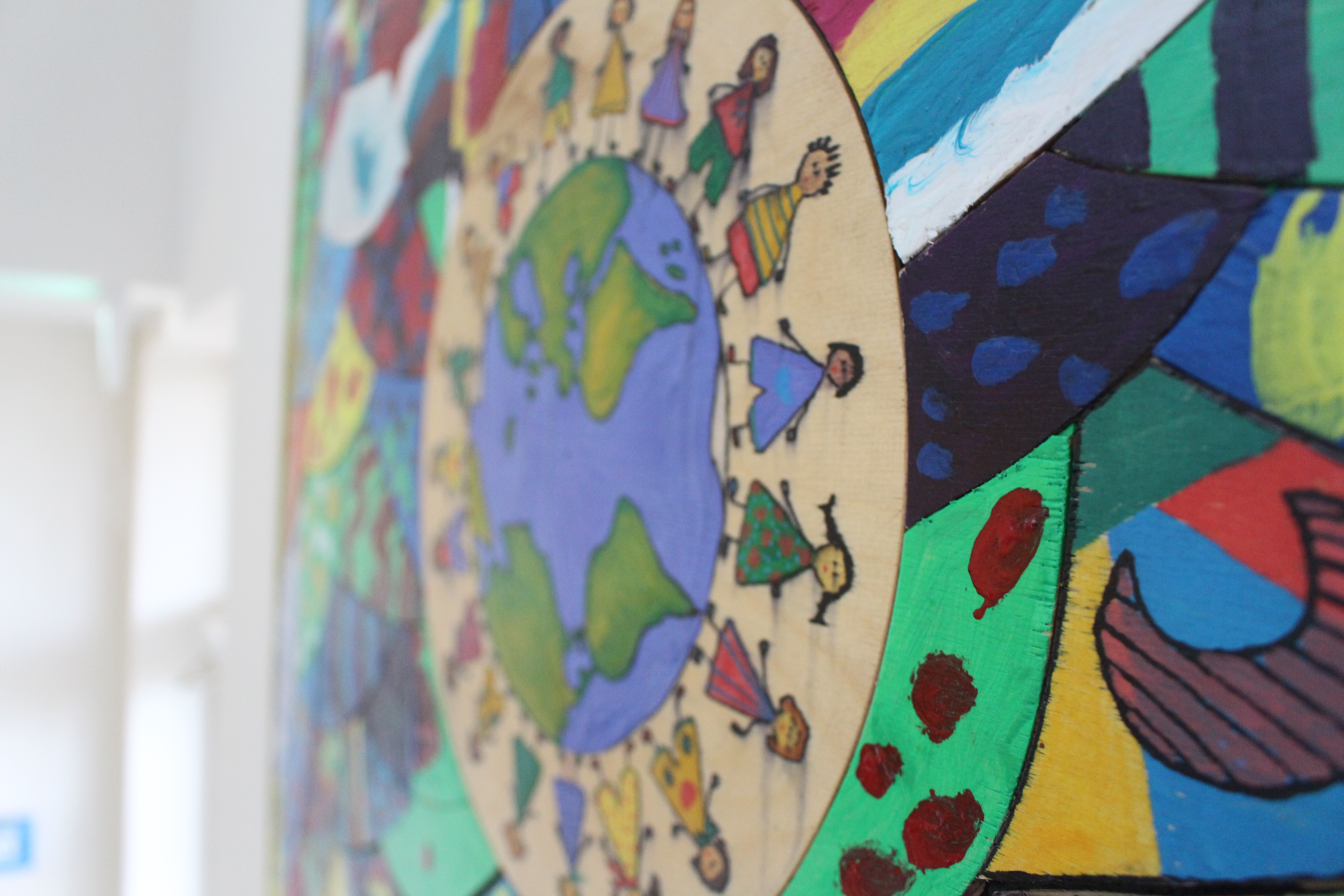 Ein Gemälde an der Wand zeigt viele Kinder mit unterschiedlicher Hautfarbe, die sich an der Hand halten.